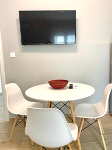 uma mesa branca com cadeiras e uma televisão na parede em Eternal Suites Edessa em Édessa