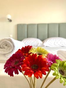 Ein paar Blumen in einer Vase auf einem Bett in der Unterkunft Eternal Suites Edessa in Edessa