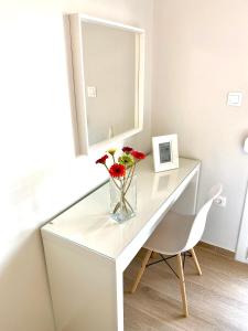 Un escritorio blanco con un jarrón de flores. en Eternal Suites Edessa, en Édessa