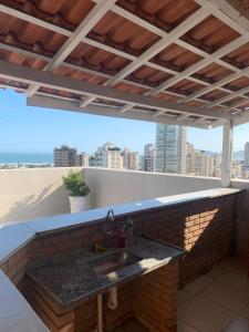 a kitchen counter with a sink on a roof at Cobertura com piscina e churrasqueira - Guarujá in Guarujá +34 photos