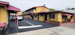 Une rangée de bâtiments avec des voitures garées dans un parking dans l'établissement RUBY MOTEL, à Long Beach
