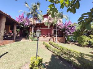 une maison rose avec un palmier dans la cour dans l'établissement Chacara 70 km de SP - A tranquilidade do campo com conforto da cidade, à Itupeva