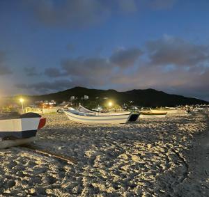 Posada Sueños De Verano في فلوريانوبوليس: مجموعة من القوارب جالسة على شاطئ في الليل