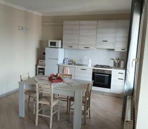 una cocina con mesa y sillas y una cocina con armarios blancos. en La Casa di Ermes - Ampio luminoso appartamento a due passi dal centro, en San Remo