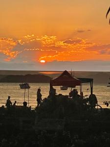 um grupo de pessoas na praia ao pôr do sol em Posada Sueños De Verano em Florianópolis