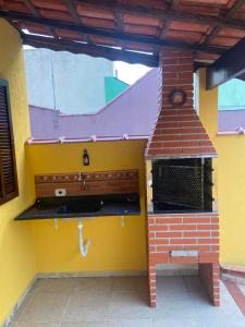 Il comprend une cuisine équipée d'une cuisinière. un four en briques dans l'établissement Casa térrea em Caraguatatuba, à Caraguatatuba