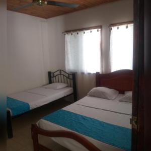 two beds in a room with a window at Cabaña Midas Rodadero in Santa Marta