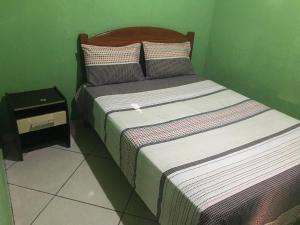 Cama en habitación con pared verde en Casa Laranja, en Vale do Capao