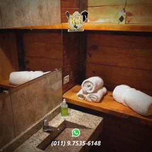 Un baño con lavabo, espejo y toallas. en POUSADA HARAS K&k, en Pinhalzinho