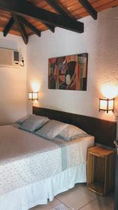 a bedroom with a bed and a painting on the wall at Casinha Astral - Praia da Ferrugem in Garopaba