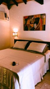 a bed in a room with a painting on the wall at Casinha Astral - Praia da Ferrugem in Garopaba