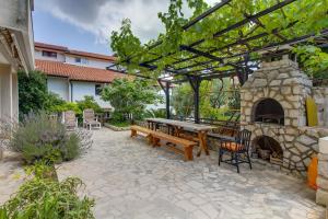 a patio with a picnic table and a stone fireplace at Apartments Eli - 100 m from sea in Mali Lošinj