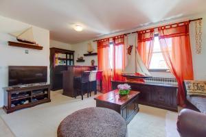 a living room with a couch and a tv and a table at Apartments Eli - 100 m from sea in Mali Lošinj