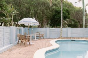 a patio with a table and an umbrella next to a pool at The Blue Water Motel in Kingscliff