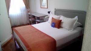 1 dormitorio con cama con almohadas blancas y escritorio en Hotel Presidente, en Santiago