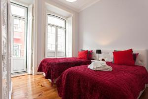 - 2 lits dans une chambre blanche avec des draps rouges dans l'établissement Traditional & Charm house in Graça, à Lisbonne