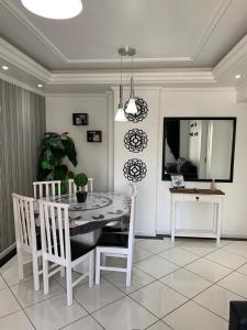 une salle à manger avec une table et des chaises blanches dans l'établissement Apartamento Praia Central, à Balneário Camboriú