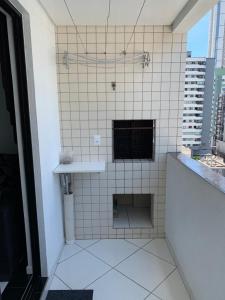 a white tiled bathroom with a sink and a window at Apartamento Praia Central in Balneário Camboriú