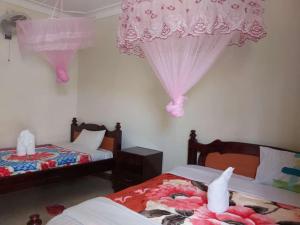 two beds in a room with pink curtains at Famko Hotel Lira- Uganda in Lira +29 photos