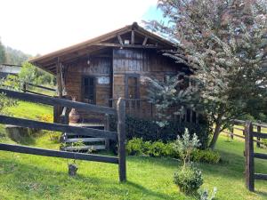 una cabina di legno in un campo con recinzione di Acogedora cabaña de madera en la naturaleza para desconectarse a Sogamoso