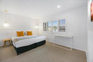 a bedroom with a bed with orange pillows and a window at Mediterranean Surfers Paradise Townhouse with BBQ in Gold Coast