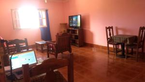 a living room with a television and a table and chairs at Imaynalla Humahuaca Hostl in Humahuaca