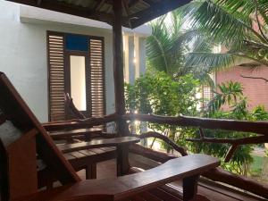 a porch with wooden benches and trees and a building at Neptune's Villa in Haad Rin