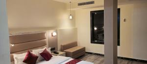 ein Hotelzimmer mit einem Bett mit roten Kissen in der Unterkunft The Jamun Tree in Muzaffarpur