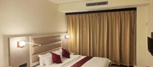 una camera d'albergo con letto e cuscini rossi di The Jamun Tree a Muzaffarpur