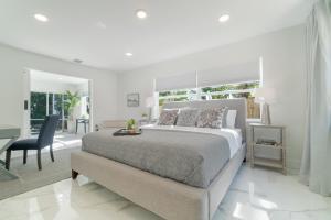 a white bedroom with a bed and a desk at Elegant 5BR West Palm Beach Home Near Beach in West Palm Beach