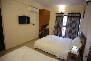 a hotel room with a bed and a television at The Lounge Business Hotel in Bangalore