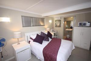 ein Schlafzimmer mit einem weißen Bett mit lila Kissen in der Unterkunft Tri-Angle B&B and Guesthouse in Adelaide
