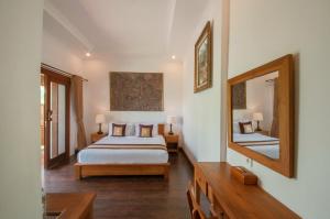 a bedroom with a bed and a large mirror at Uma Dawa Resort and Spa in Ubud