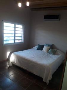 1 dormitorio con 1 cama blanca y ventana en Vulgata en San Pedro