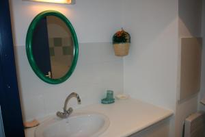 a bathroom sink with a green mirror on the wall at Gaindeguia Studio in Cambo-les-Bains