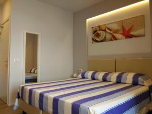 - une chambre avec un lit à rayures bleues et blanches dans l'établissement Hotel l'Approdo, à Porto Azzurro