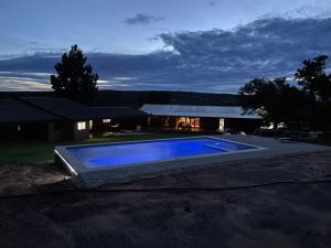 a large blue swimming pool in front of a house at Kransberg Country Lodge Guest Farm in Thabazimbi