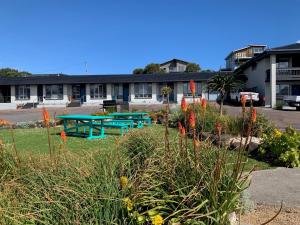 un grupo de mesas de picnic frente a un edificio en Southern Ocean Motor Inn, en Port Campbell