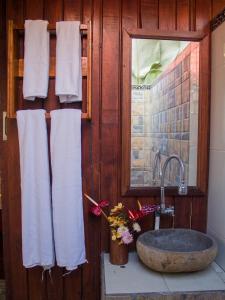 uma casa de banho com lavatório, espelho e toalhas em Da'Kayu Bali Homestay em Munduk