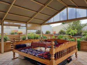 ein großes Holzbett unter einer überdachten Terrasse in der Unterkunft Spacious Holiday Home - Waikerie in Waikerie