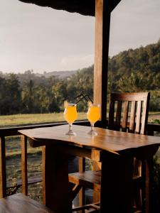 two glasses of orange juice sitting on a wooden table at Da'Kayu Bali Homestay in Munduk