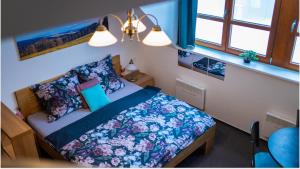 a bedroom with a bed with a blue comforter and pillows at Skiapartma - Říčky v Orlických horách in Říčky