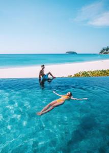 a man and a woman swimming in the ocean at The Shore At Katathani - Adult Only - SHA Extra Plus in Kata Beach