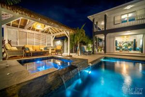 a swimming pool in the backyard of a house at night at LA VILLA ROSAYA - Piscine & Jacuzzi in Saint-Pierre