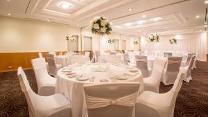 a banquet room with white tables and chairs and flowers at Crowne Plaza Perth by IHG in Perth +105 photos