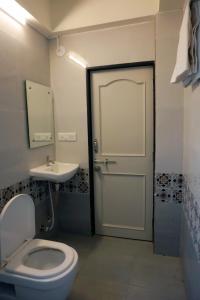 a bathroom with a toilet and a sink and a door at Hotel Nova SK in Rajkot
