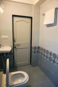 a bathroom with a toilet and a sink and a door at Hotel Nova SK in Rajkot