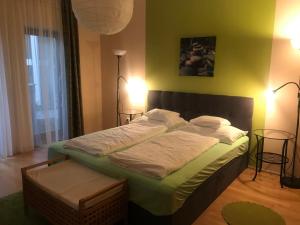 una camera da letto con un letto grande con lenzuola bianche di Feng Shui Wellness Apartmanház Hévíz a Hévíz