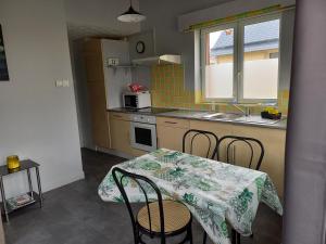 eine Küche mit einem Tisch und Stühlen sowie einem Tisch und einem Waschbecken in der Unterkunft Maison au pied du Mont Saint Michel in Pontorson