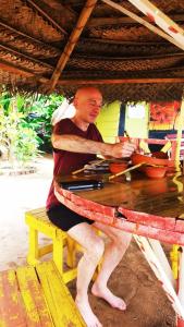 a man is sitting on a picnic table at Rosa Shashi Cabanas in Galle